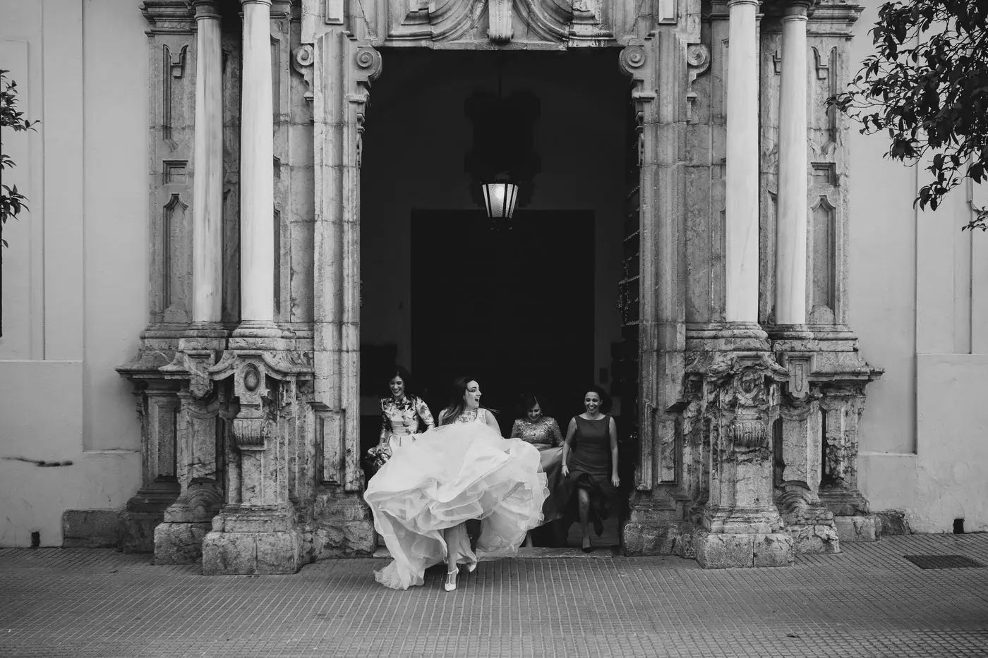 La novia saliendo corriendo del portal con sus amigas