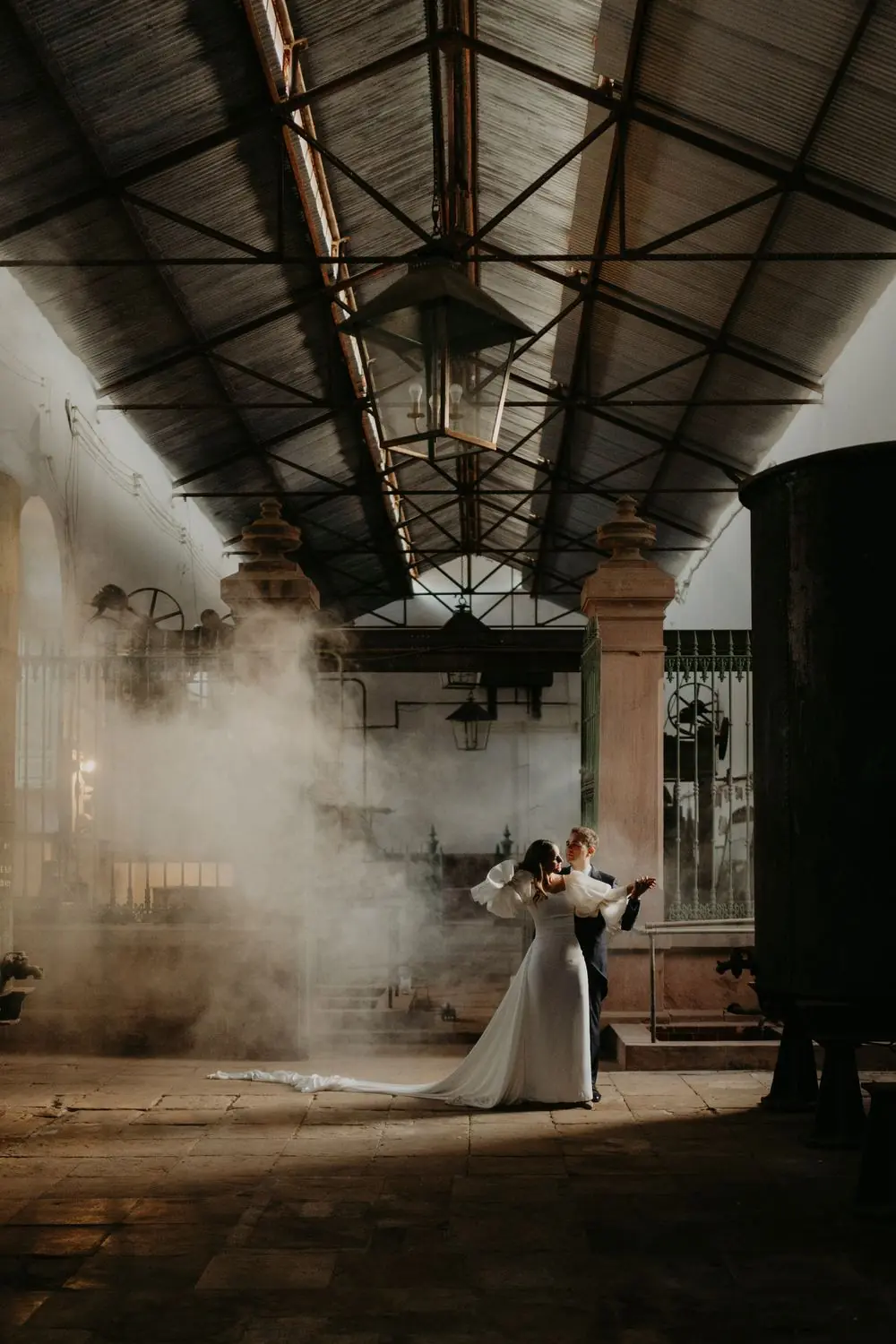 Los novios bailando entre el humo en una nave industrial
