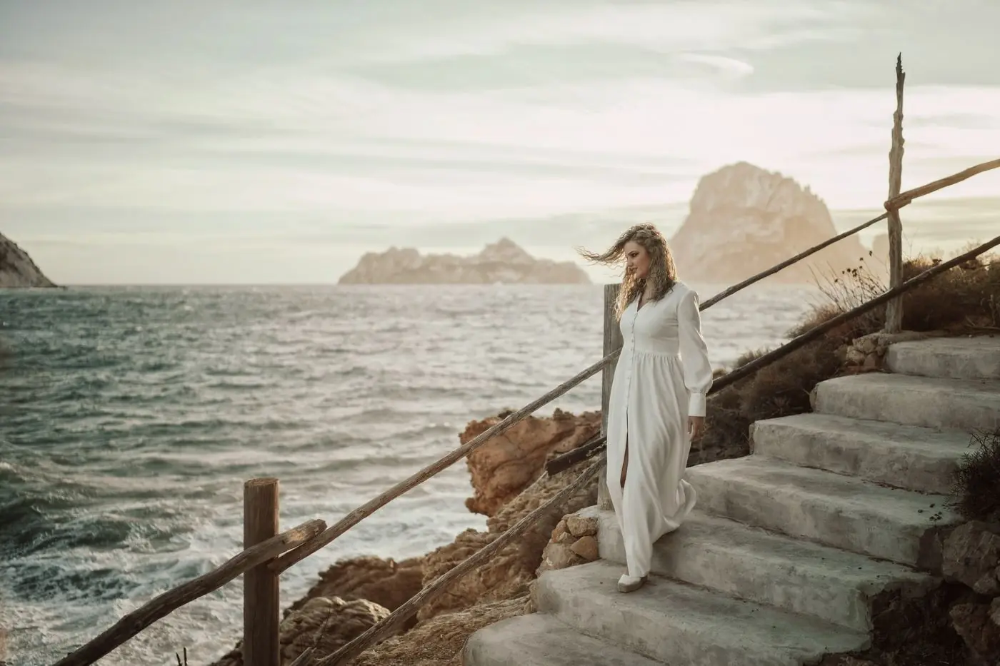 Ella baja unas escaleras junto al mar al atardecer