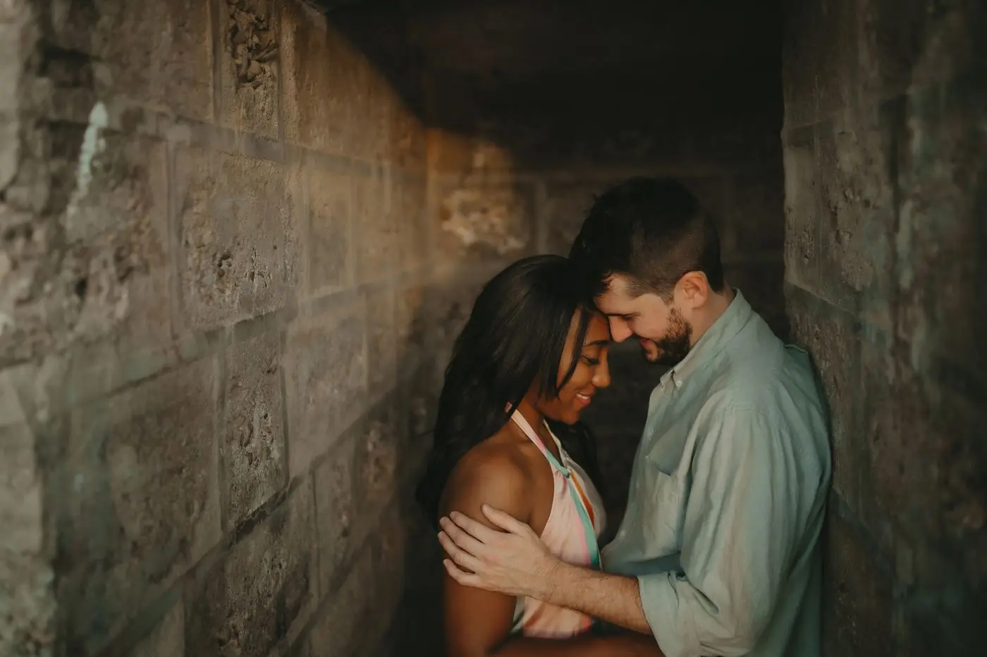 Una pareja frente con frente apoyada en un muro de piedra